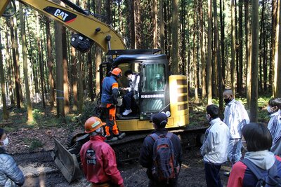 R03.10.26 沼田市立利根中学校3年生の生徒さんが、総合学習の一環で、間伐作業現場で、見学や伐採の体験をしました。写真は、高性能林業機械ハーベスタの複雑な操作をオペレータが説明中。
